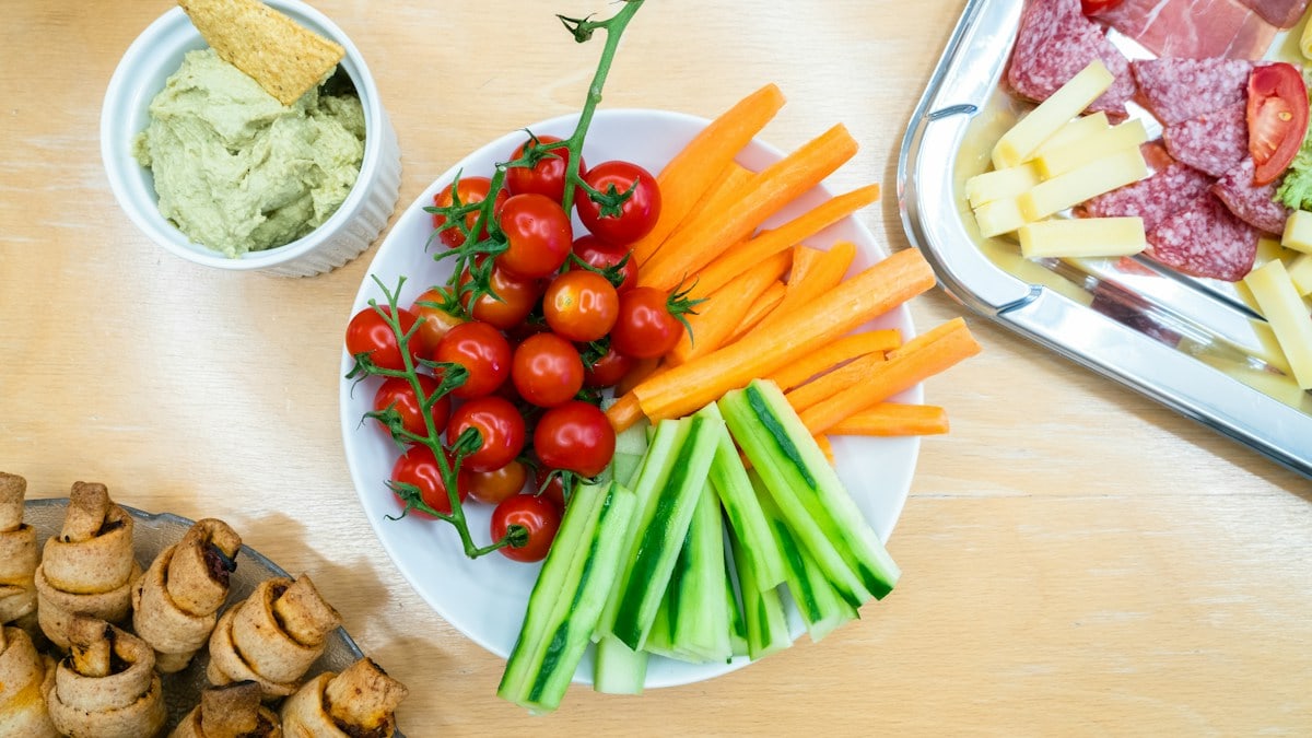 slices of carrots, zucchini, and cherry tomatoes on round white ceramic bowl